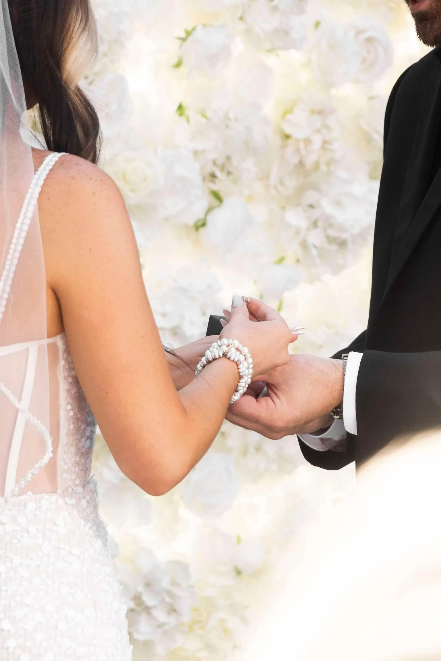 Bride and groom holding hands at the flower wall
