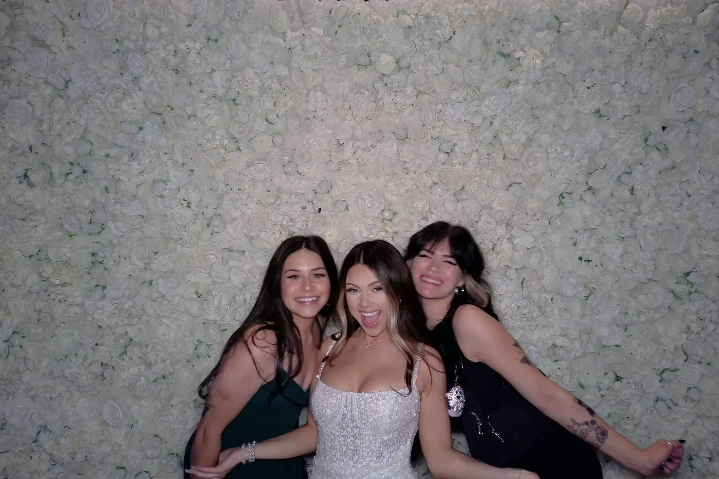 Friends in party dresses posing at the flower wall